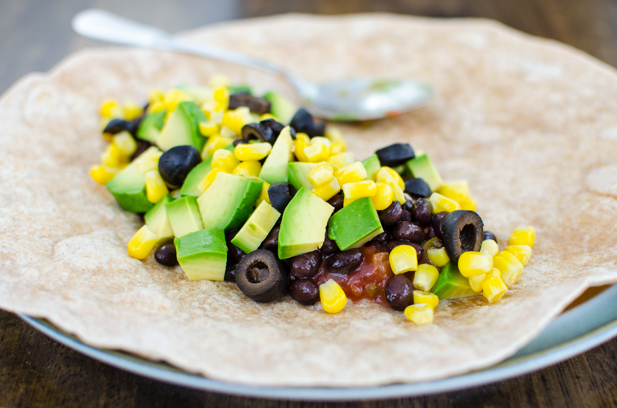 Ingredients for black bean wrap on an open tortilla