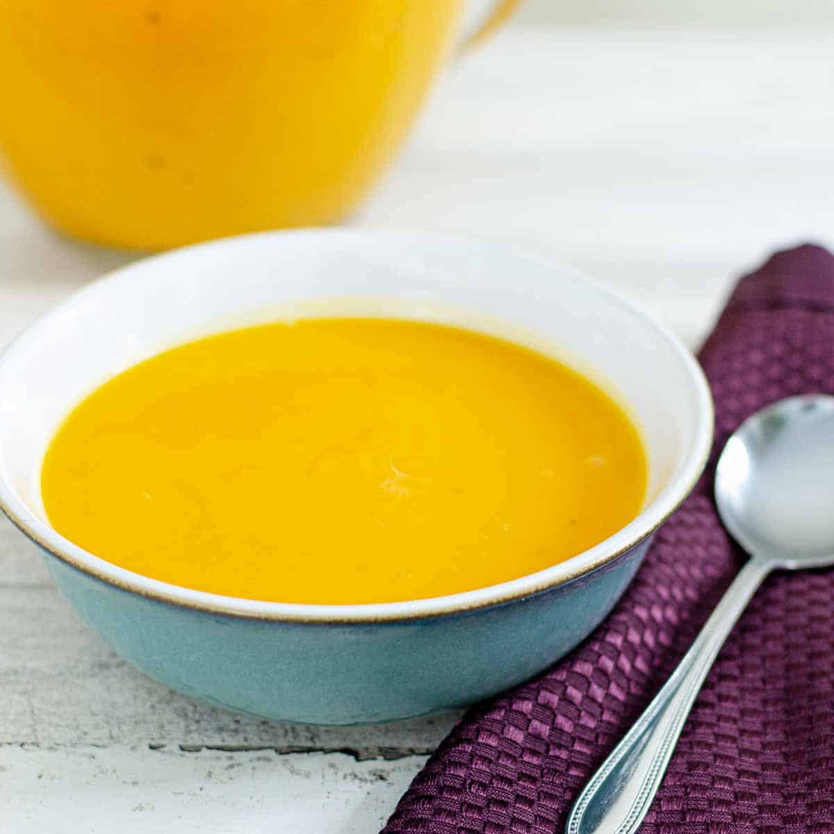bowl of instant pot butternut squash soup with a serving bowl in the background