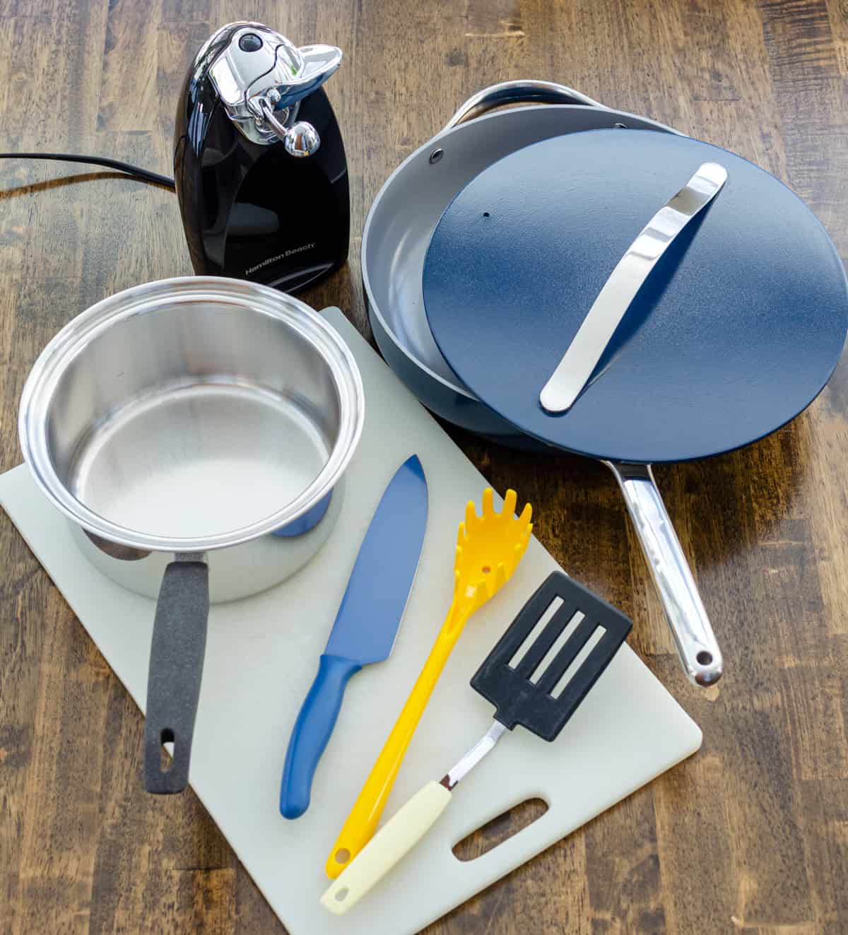 things needed to make simple coconut curry, including a sauté pan, saucepan, cutting board, chef's knife, spatula, pasta spoon and can opener